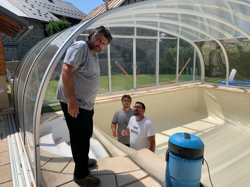 Travailleur d'entretien de la piscine avec produits et outils de nettoyage chimiques sur table en bois et fond bleu