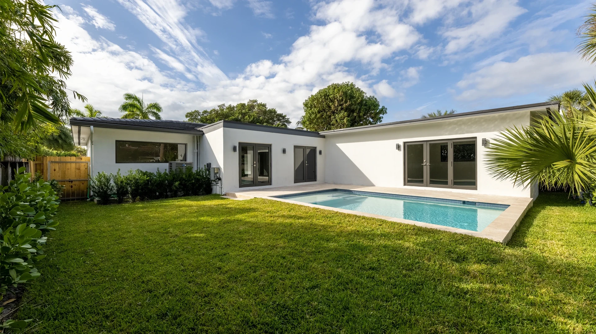 Piscine résidentielle extérieure avec abri-véranda en structure métallique noire et panneaux transparents