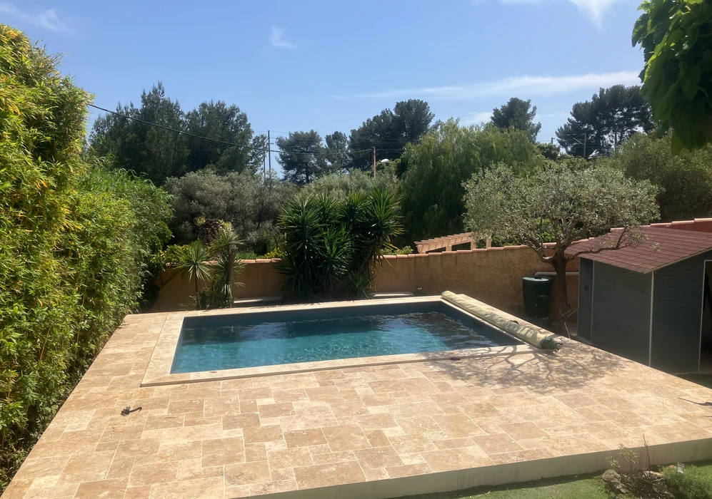 Piscine extérieure rectangulaire à angles arrondis installée dans jardin résidentiel avec terrasse en bois exotique